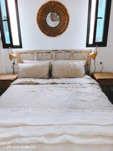 1 dormitorio con cama blanca y espejo en la pared en Casa Tasya Corralejo Centre, en Corralejo