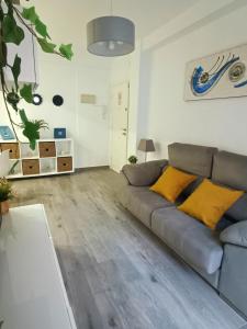 a living room with a gray couch and yellow pillows at BEACH&GARDEN in Málaga