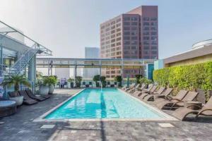 une piscine avec des chaises longues et un bâtiment dans l'établissement The Downtown Suite, à Los Angeles
