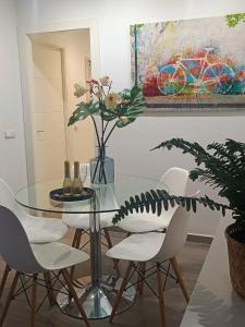 a glass table with white chairs and a vase with flowers at BEACH&GARDEN in Málaga