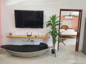 a living room with a tv and a hammock in a room at Casa Gacela Cozumel in Cozumel