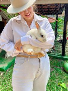 una mujer sosteniendo un conejo blanco en su cinturón en Hotel Fazenda Golden Park Campos do Jordão, en Campos do Jordão