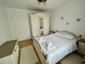 1 dormitorio con cama blanca y lámpara de araña en Apartament Central, en Vişeu de Sus