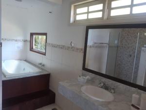 a bathroom with a sink and a tub and a mirror at Pousada Éden in Angra dos Reis