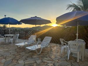 a group of chairs and umbrellas on a patio with the sunset at Recanto da Felicidade in São Lourenço