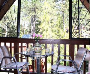 - une table sur une terrasse couverte avec des chaises et un vase fleuri dans l'établissement Cottage Tatry so saunou, à Tatranska Strba