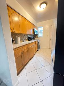 uma cozinha com armários de madeira e piso em azulejo branco em Mokulele em Miami