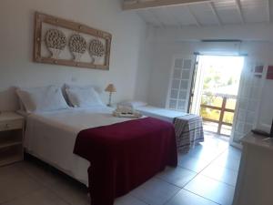 a bedroom with a large white bed and a window at Pousada Éden in Angra dos Reis