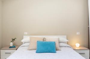 un letto bianco con un cuscino blu sopra di Appartamento Al Castello Avezzano ad Avezzano