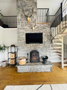 sala de estar con chimenea de piedra y TV en Conree Lodge en Castlemaine