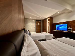 a hotel room with two beds and a flat screen tv at Hôtel Restaurant & Spa Les Planets in Les Rasses