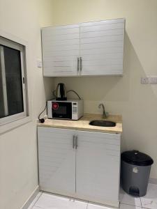 a kitchen with a sink and a microwave on a counter at أجنحة دارنـــــا للـــشقق الــمــفــروشــة in Abha