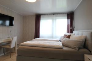 Schlafzimmer mit einem Bett, einem Fenster und einem Schreibtisch in der Unterkunft STRANDLIEBE 100 qm Gartenwohnung (eingezäunt), 15 Gehminuten zum Strand in Neukirchen