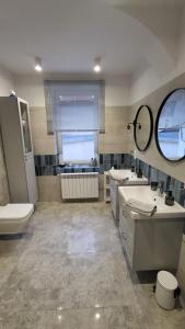 a bathroom with two sinks and a toilet and a mirror at Apartament Monopoli in Ustka