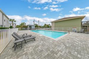 a swimming pool with benches next to a fence at Completely Coastal Spacious townhome with Harbor views a Dock and community Pool in Fort Walton Beach