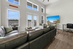 a living room with a large couch and windows at Completely Coastal Spacious townhome with Harbor views a Dock and community Pool in Fort Walton Beach