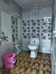a bathroom with a toilet and a pink bucket at Shanti Kunj Yatri Niwas in Ayodhya