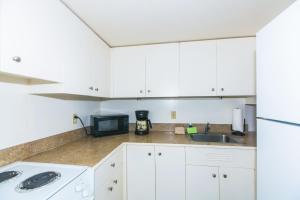 a kitchen with white cabinets and a sink and a microwave at Ilikai Tower 1127 Yacht Harbor View 1BR in Honolulu