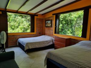 1 dormitorio con 2 camas y 2 ventanas en Finca en Sopetran, Ant en Sopetran