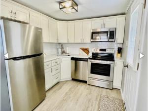 uma cozinha com armários brancos e um frigorífico de aço inoxidável em Patel em Beach Haven