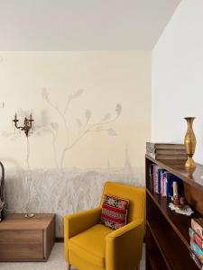 a yellow chair in a living room with a wall at Le allodole in Bellano