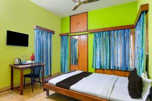 um quarto com uma cama e uma secretária com um computador em OYO Ramya Guest House em Calcutá