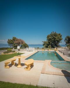 a pool with tables and benches next to the water at Zeus Sea View Villa with Private Pool, Afytos in Afitos