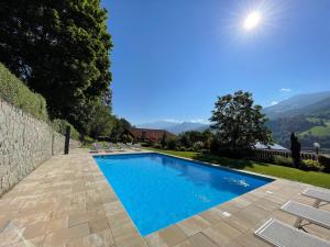 einen Pool mit Stühlen und einer Steinmauer in der Unterkunft TANOVINUM APARTMENTS Neue moderne Apartments in der Nähe von Klausen Freibad Südtirol Card inklusive in Villanders