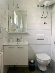 a white bathroom with a toilet and a mirror at Apartment Ponoš in Krk
