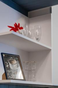 a shelf with wine glasses and a picture on it at Блакитна студия, Південний вокзал 5 хвилин in Kharkiv