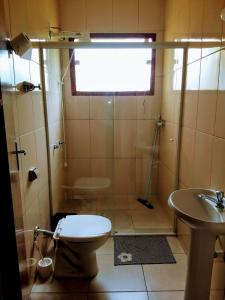 ein Bad mit einer Dusche, einem WC und einem Waschbecken in der Unterkunft Hostel Guaxinim in Caraguatatuba