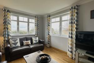 a living room with a couch and two windows at No2 The Links Apartment, Brora in Brora