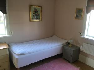 1 dormitorio pequeño con 1 cama blanca y 2 ventanas en Enköping Cottage en Enköping
