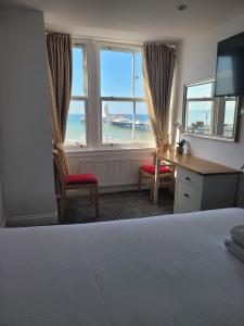 a bedroom with a bed and a desk and windows at Atlantic Seafront in Brighton & Hove