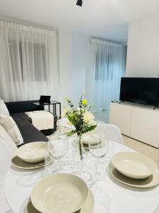 una mesa blanca con platos y gafas y una sala de estar. en Ático en Sanlúcar de Barrameda, en Sanlúcar de Barrameda