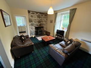 a living room with two couches and a fireplace at Ness View Cottage in Fort Augustus
