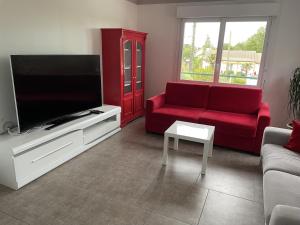 Il comprend un salon doté d'un canapé rouge et d'une télévision à écran plat. dans l'établissement Chantal&Daniel, à Saint-Brévin-les-Pins