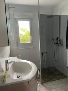 une salle de bain blanche avec un lavabo et une fenêtre dans l'établissement Chantal&Daniel, à Saint-Brévin-les-Pins
