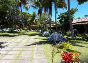 une cour avec des palmiers, des tables et des fleurs dans l'établissement Pousada Verdes Mares, à Santa Cruz Cabrália