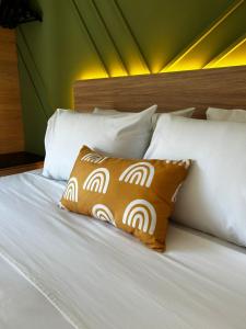 a bed with a brown pillow and white pillows at Flat Praia Century Camburi in Vitória