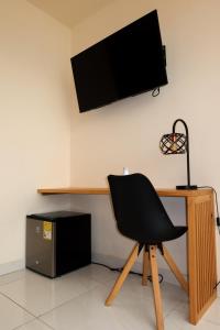 a black chair sitting in front of a desk with a television at Hotel París in Villeta