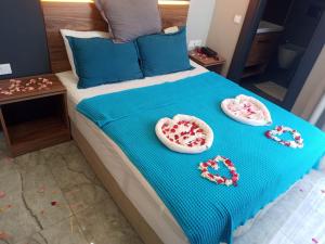 a bed with a blue blanket and two plates with hearts at Başar hotel in Erdemli