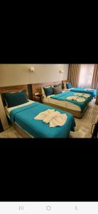three beds in a room with blue sheets at Başar hotel in Erdemli