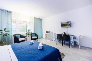 1 dormitorio con 1 cama azul, mesa y sillas en Lake Apartment 4 en Bissone