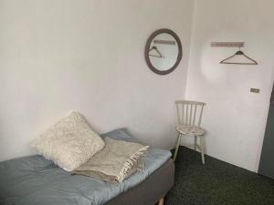 Zimmer mit einem Bett, einem Spiegel und einem Stuhl in der Unterkunft Kongshøjgaard in Farsø