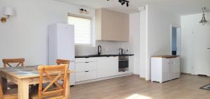 クラクフにあるMiriam Apartment Kraków Borkowskaの白いキャビネット、木製テーブルと椅子付きのキッチンが備わります。