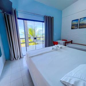 a bedroom with a large bed and a large window at Pousada Boa Sorte in Cumuruxatiba