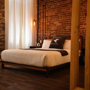 a bedroom with a bed with a brick wall at Maison Évangéline by Bower Boutique Hotels in Moncton
