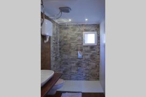y baño con ducha y pared de piedra. en Mavric Cabin, en Ulcinj