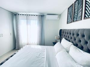 a bedroom with a large white bed and a window at DEE-LOFT 53 in Windhoek